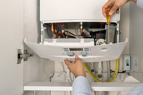 HVAC technician repairing an indoor boiler in Bountiful
