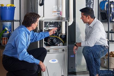65df8c11f3e4c468cbd351a5_furnace repair vs replacement – Copy HVAC technician explaining furnace repair and maintenance to a homeowner in Bountiful, UT